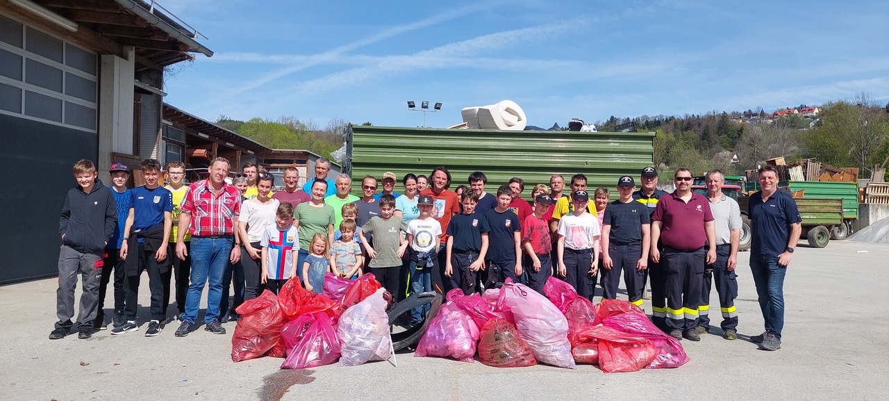 Zu sehen ist: eine Gruppe von Menschen mit Müllsäcken vor einem Müllauto