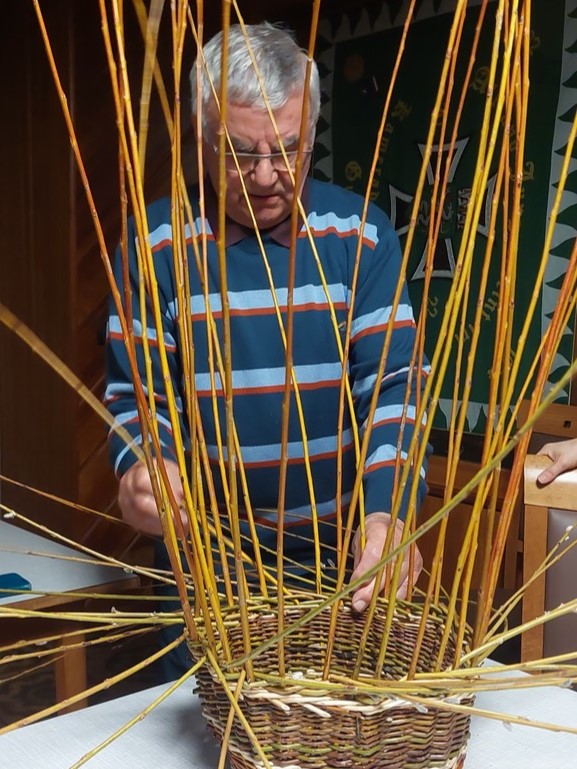 Zu sehen ist: eine Person beim Weidenkorbflechten